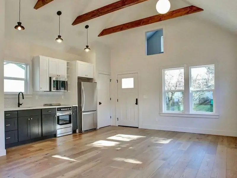 Interior of a new backyard ADU with a kitchen, vaulted ceiling and wood floors