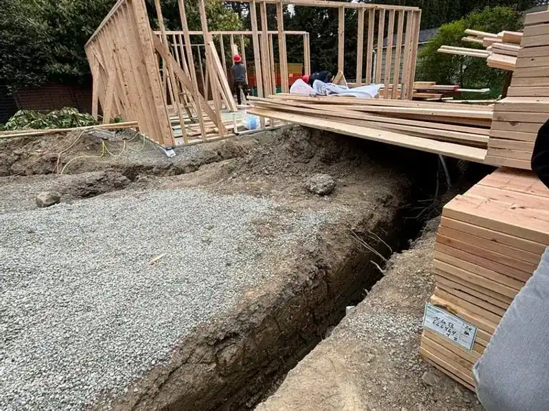 ADU wall framing going up beside a foundation trench