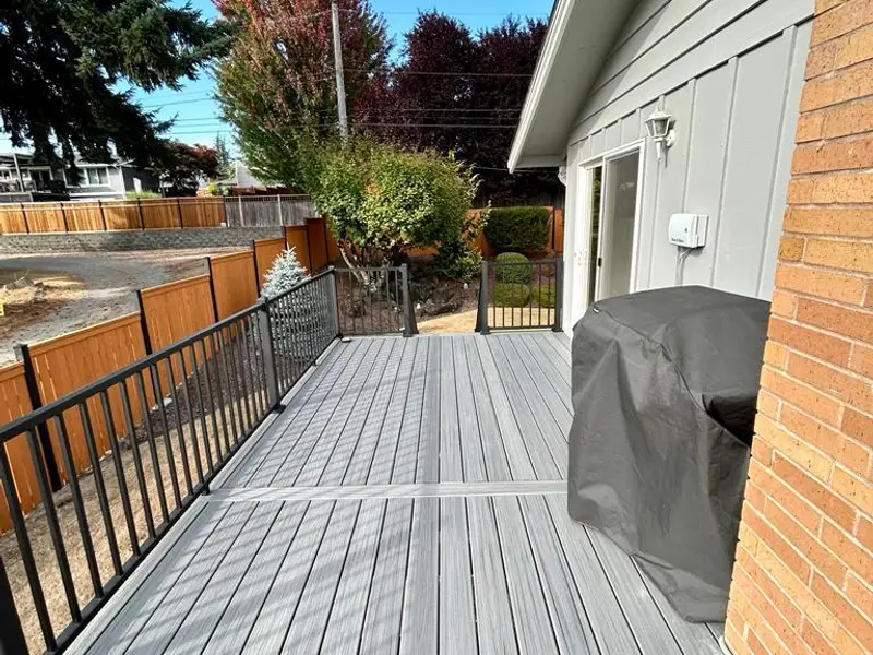 Gray composite deck along a house wall with a black metal railing