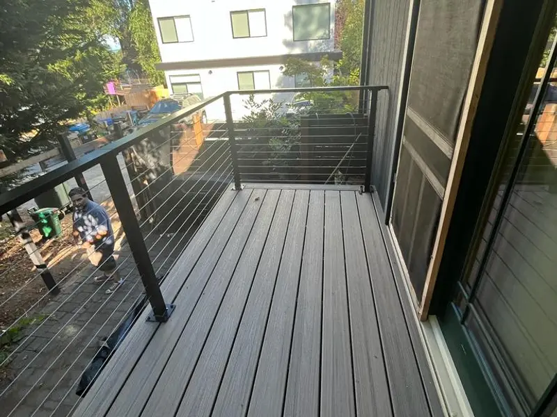 Gray composite deck with cable railing along sliding doors