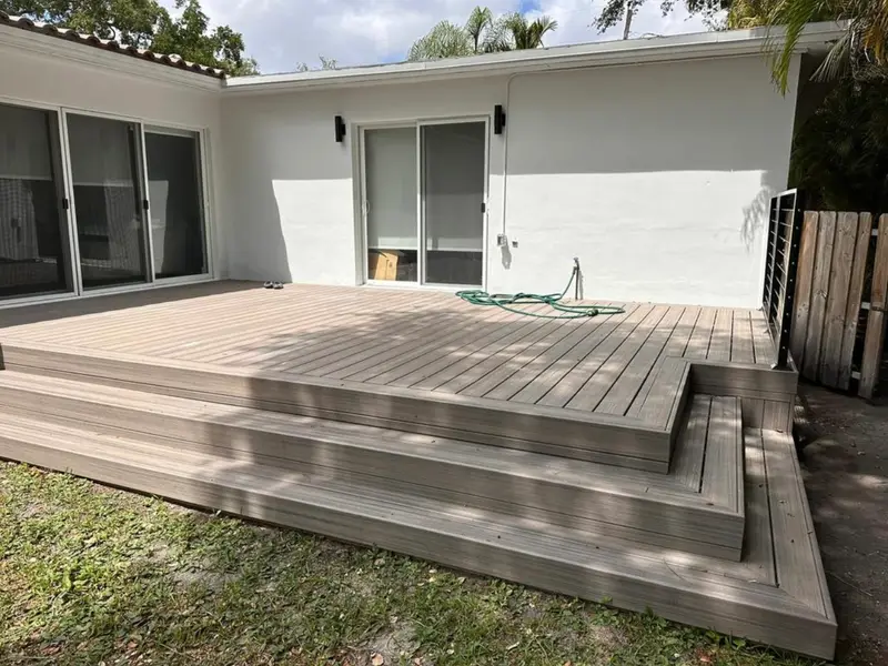 Composite deck with wide steps running along a white stucco house wall