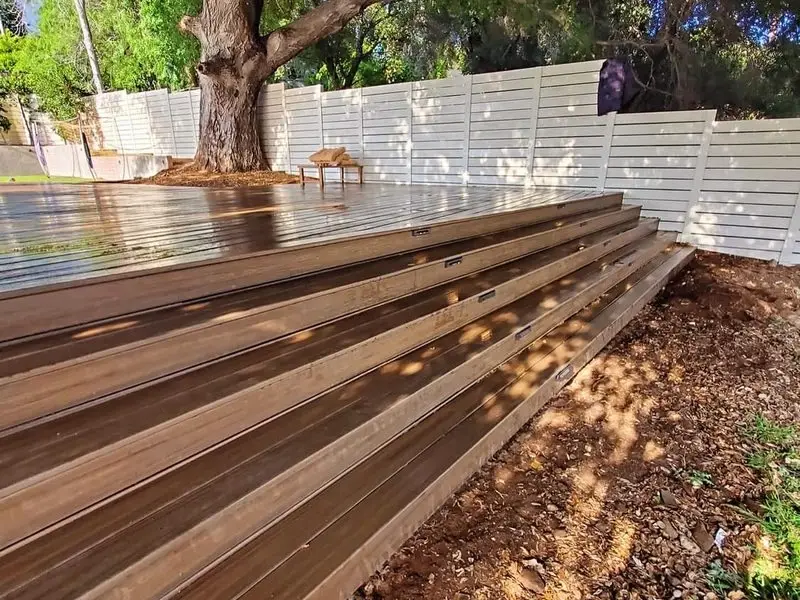 Wood deck with wide wood steps stepping down a sloped backyard