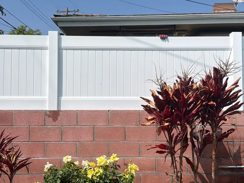 New white vinyl fence on top of a block wall