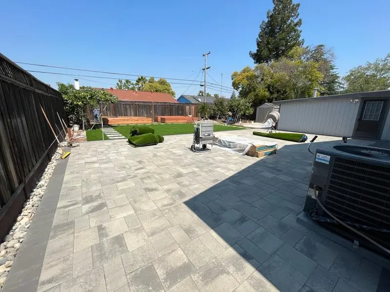 Gray paver patio along the side of a house