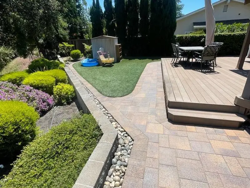 Backyard pavers beside a raised deck
