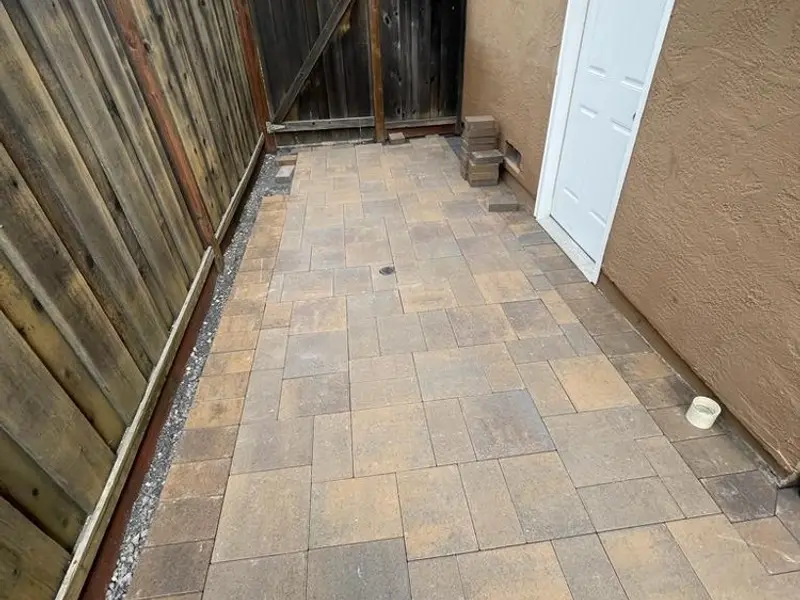 Paver side yard leading to a white door