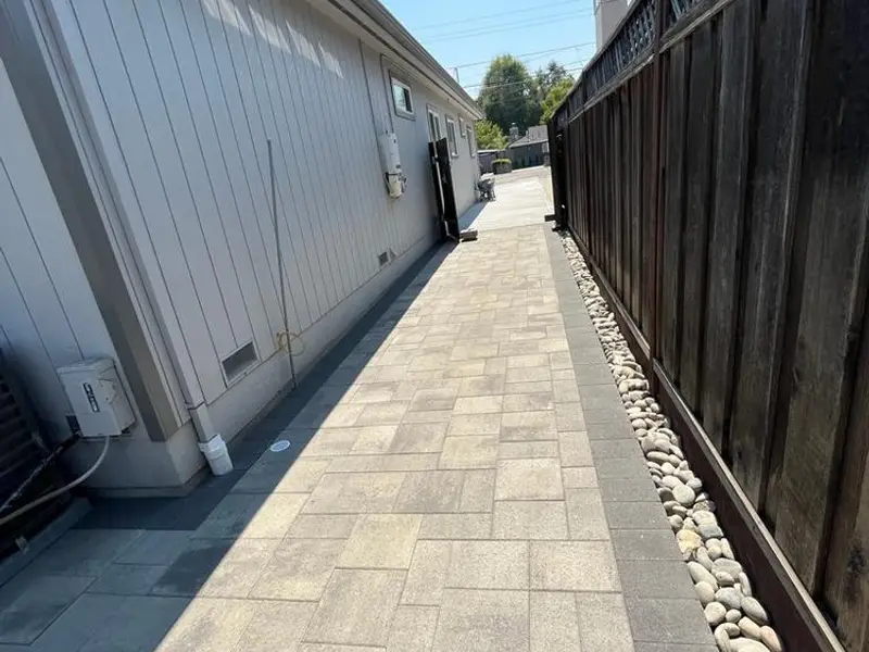 Long paver walkway between a house and a fence