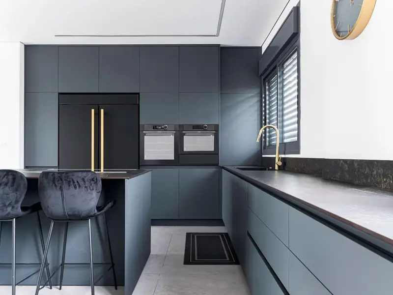 Modern kitchen with dark gray flat-panel cabinets, wall ovens and an island with bar stools