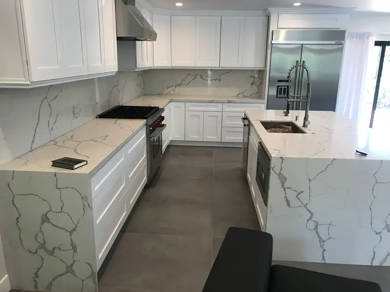 White shaker kitchen with marble-look quartz counters and a waterfall island