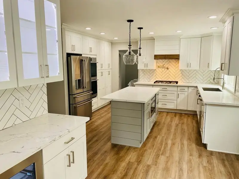 White kitchen with a gray shiplap island, pendant lights and a herringbone backsplash