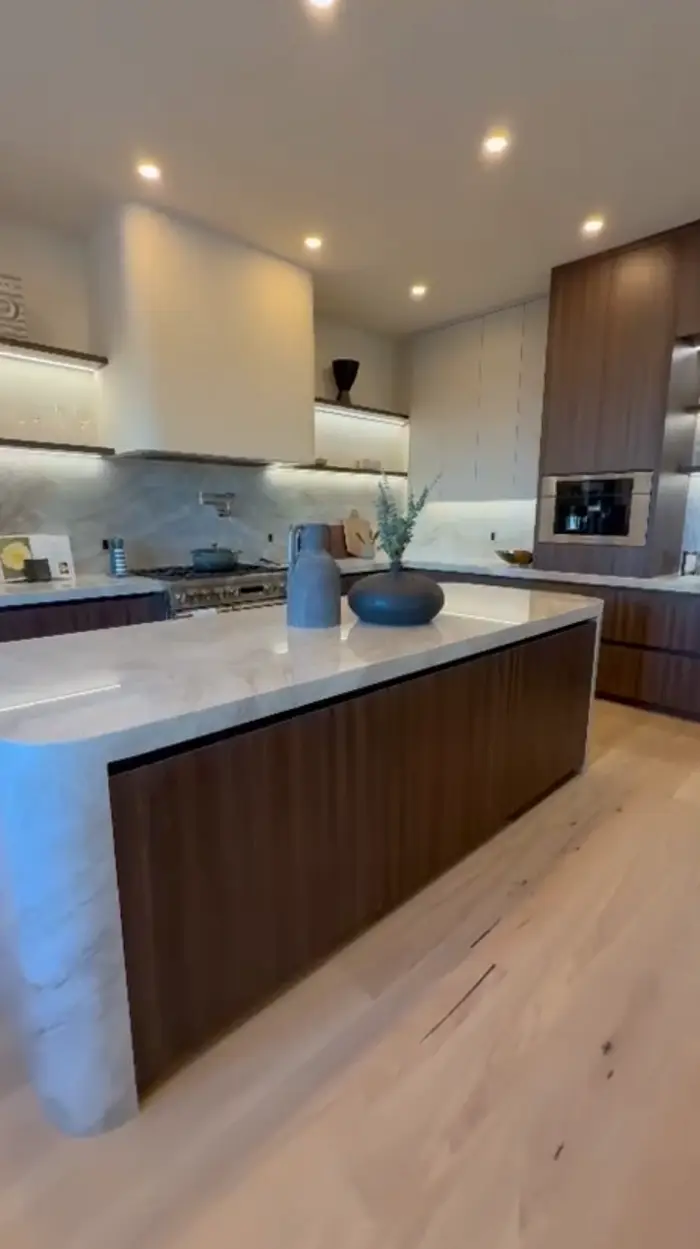 Renovated kitchen with a stone waterfall island and walnut cabinetry
